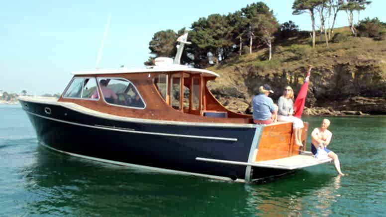 People enjoy the sun sitting on a motor boat anchored on the River Fal.