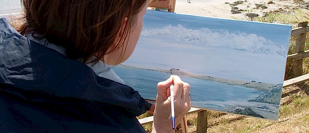 A woman paints the Cornish coast during an art holiday.