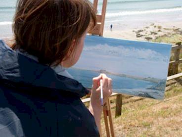 A woman paints the Cornish coast during an art holiday.