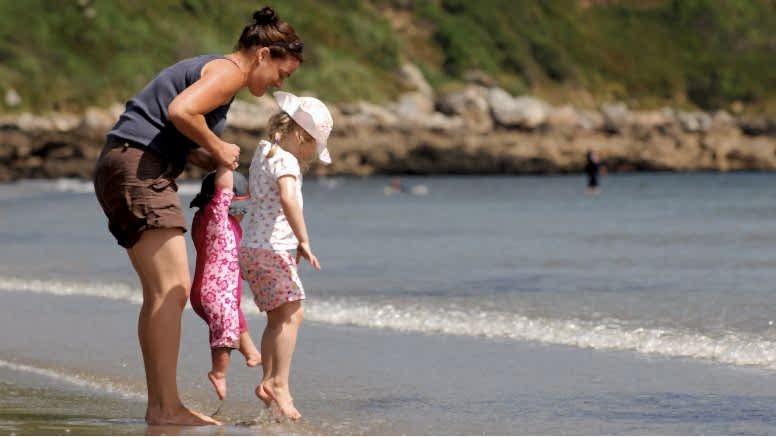 A mother and two children play on Carne Beach on the south coast of Cornwall.