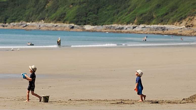Two children play on the sand of Carne Beach, a secret beach near Truro in Cornwall.