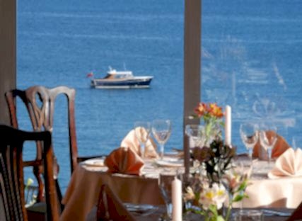 The Nare hotel dining room, with tables set and panoramic sea views.