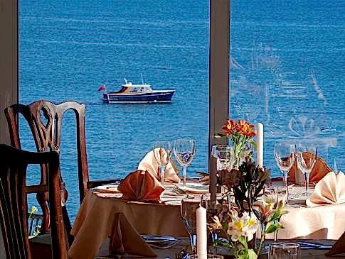 The Nare hotel dining room, with tables set and panoramic sea views.