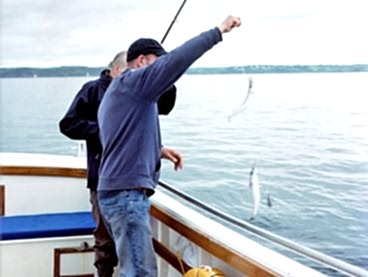 Two fishermen reel in a catch.